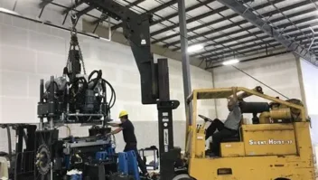 A forklift moving a part of an engine into its chassis